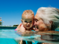 A woman in the pool playing with a baby