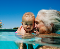 A woman in the pool playing with a baby