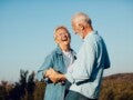 Smiling elderly woman dancing and laughing with her husband, radiating joy and confidence despite osteoporosis.